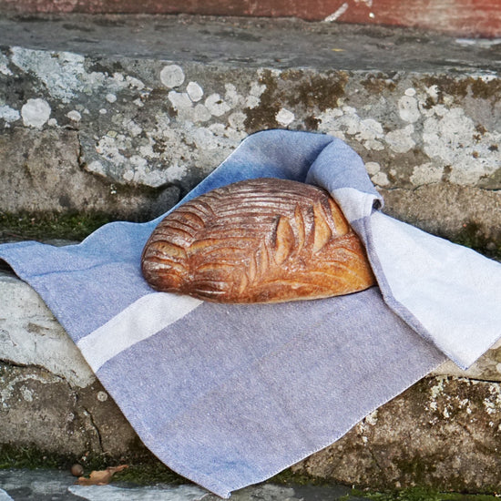 schönes, gemustertes Brot in blaues Leinentuch Linjal eingeschlagen auf einer Haustreppe aus Stein liegend