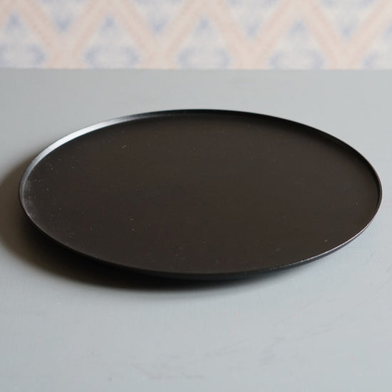 Ljusfat schwarz Kerzenteller aus Metall auf grauem Tisch mit Schwedentapete im Hintergrund
