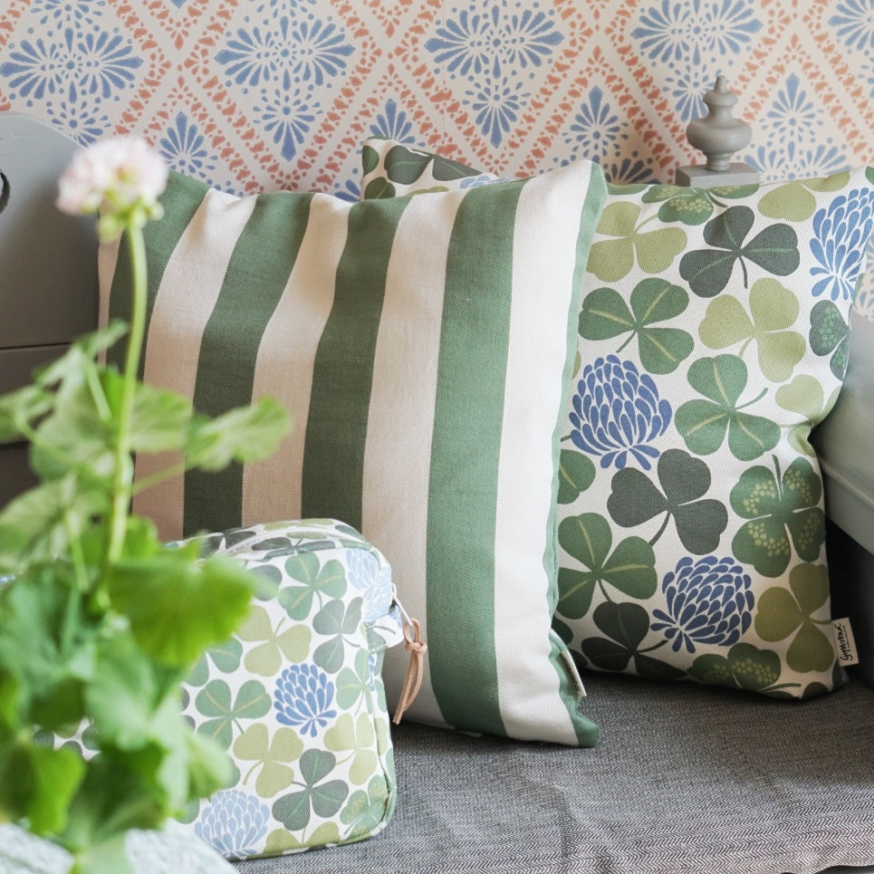 Kissen Stripe und Lyckoklöver auf Küchensofa, im Vordergrund Pelargonie und Kometikbeutel