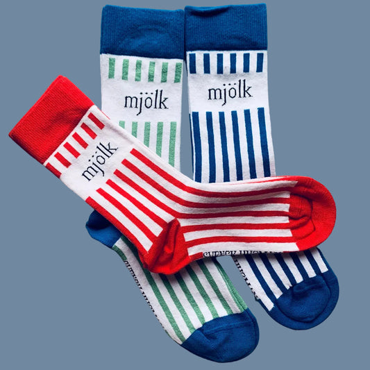 Drei Modelle Mjölk-Socken rot blau und grün vor mysblauem Hintergrund