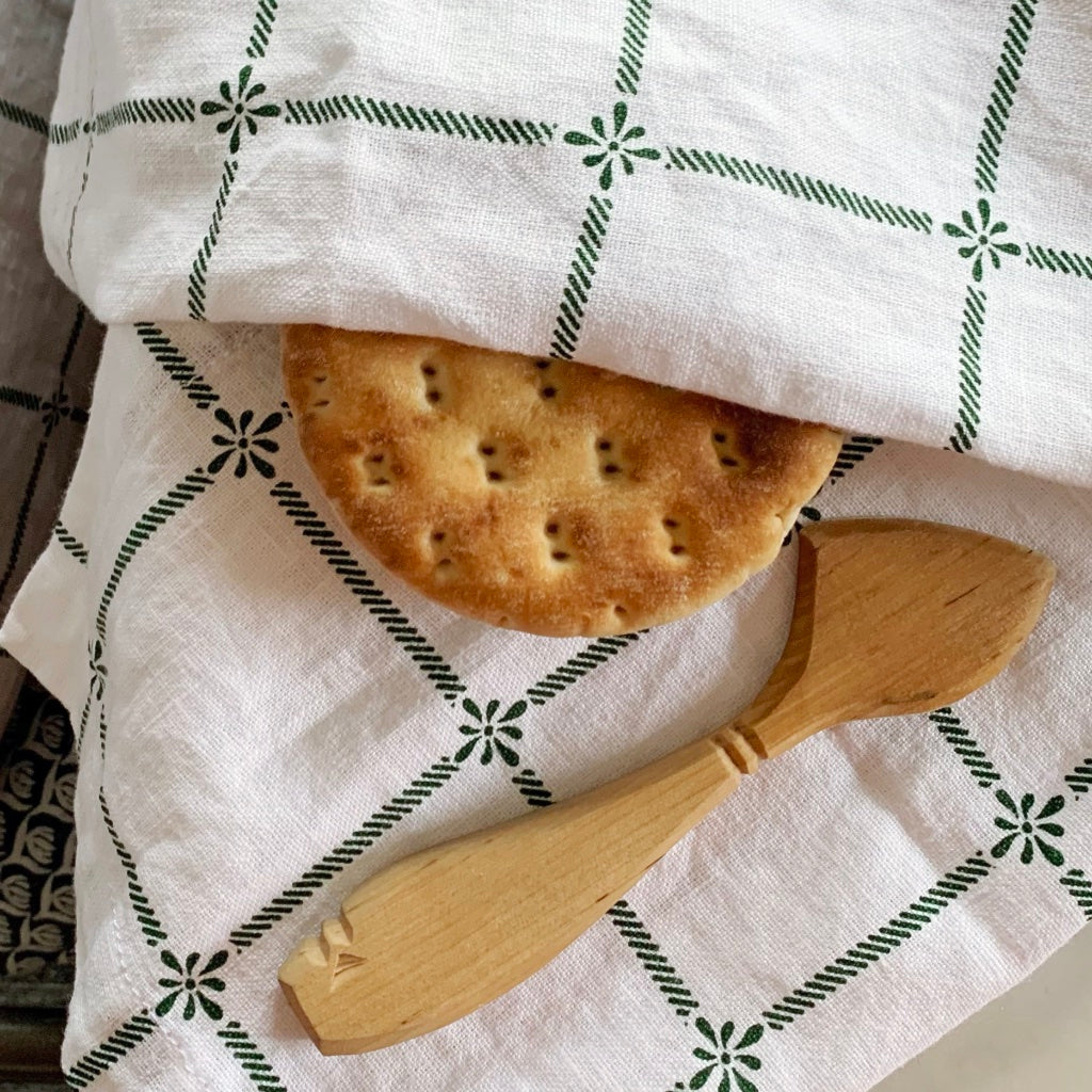 Handtuch Classic mit karierten Linien in grün um ein dünnes Brot gewickelt mit einem Buttermesser daraufliegend