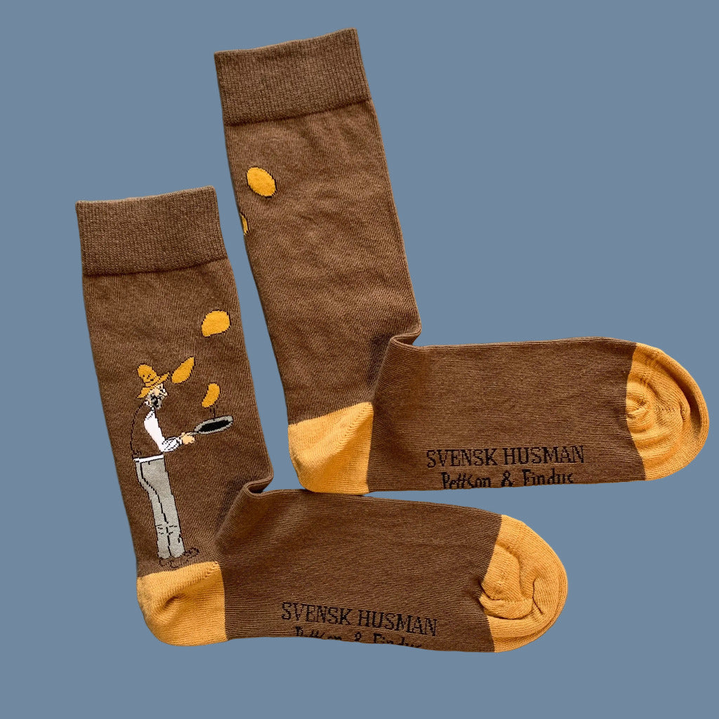Braune Socken mit orangen Spitzen und Fersen und Pettersson mit Pfanne und fliegenden Pannkuchen