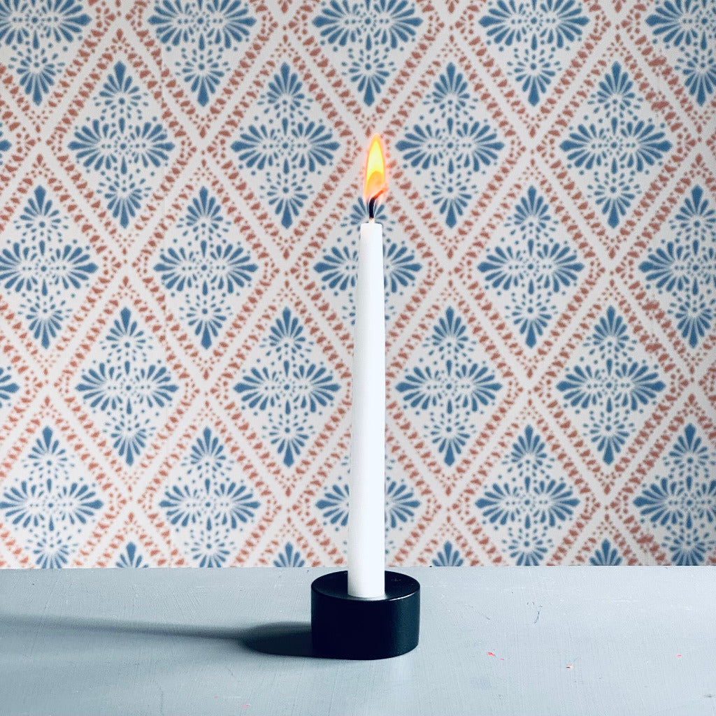 Kleiner schwarzer Kerzenständer Puck mit Kerze vor Schwedentapete
