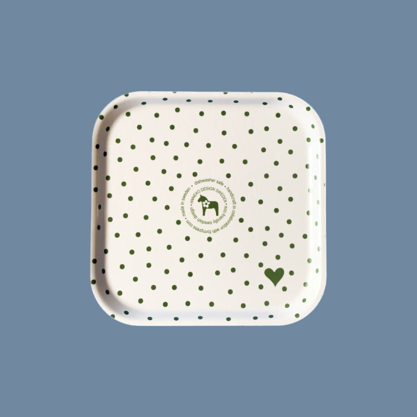 weiße Rückseite (mit grünen Punkten und Annekos Logo) des grünen Tabletts mit weißen Punkten