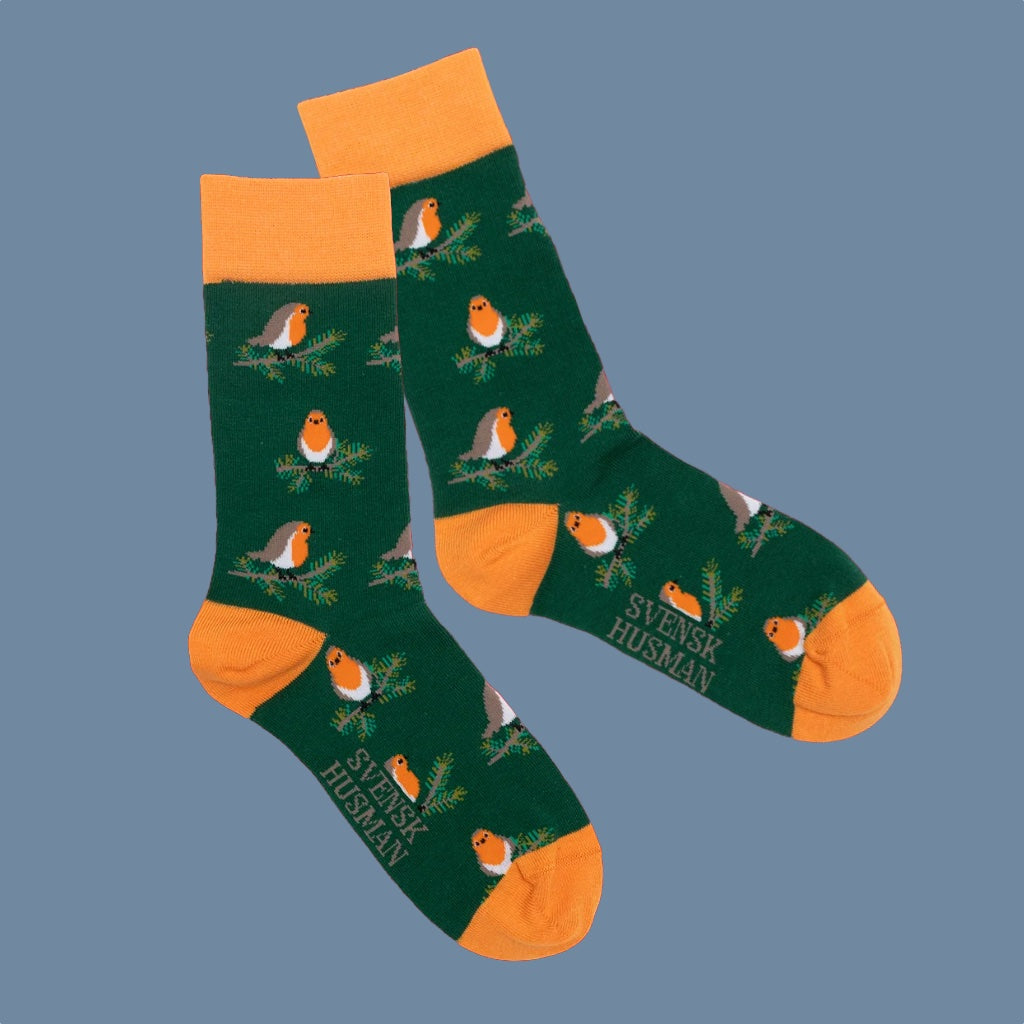 Socken mit Rotkehlchen auf grünen Tannenzweigen auf dunkelgrünem Hintergrund orangefarbenen Details