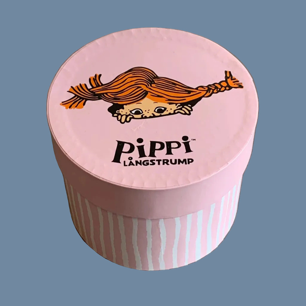 Runde Pappschachtel mit Deckel, Körper rosa weiß gestreift, auf dem Deckel ein Pippigesicht, so als schaute es aus dem Deckel