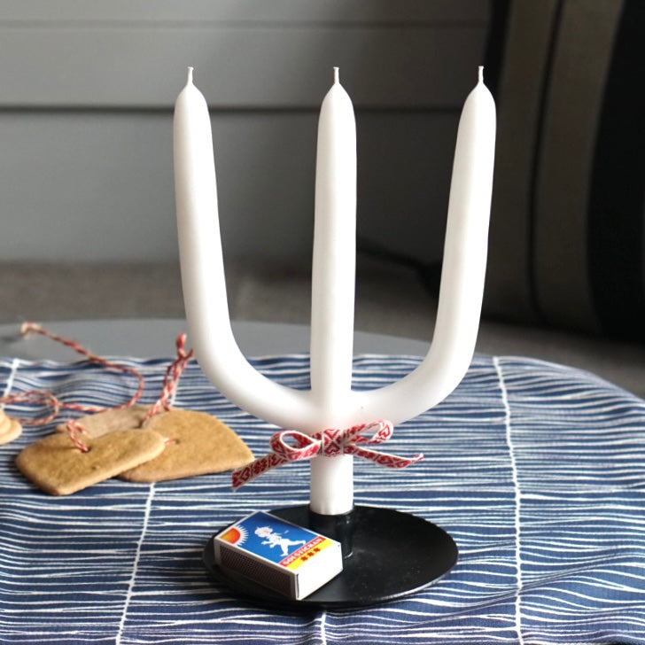 Dreiarmige, schwedische Weihnachtskerze auf Tellerleuchter auf Tisch