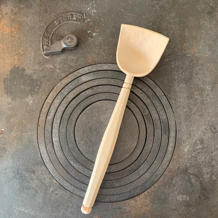 Handgeschnitzter Servierlöffel aus Birkenholz natur auf Küchenofen liegend