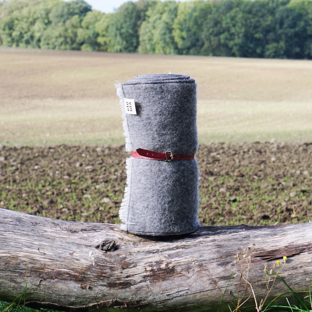 Sitzunterlage zusammengerollt und mit Ledergurt verschnürt vor Feld