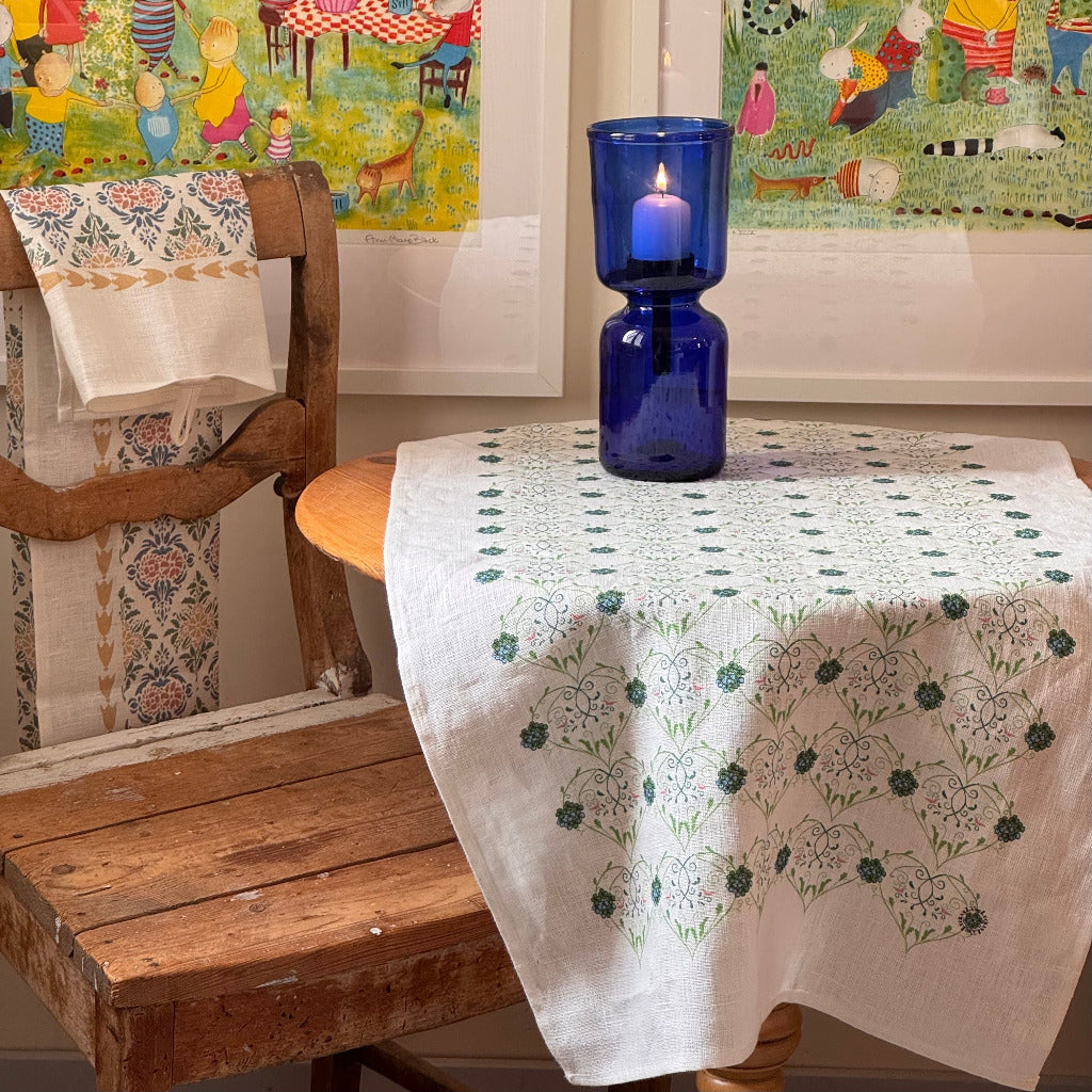 Interior Detail mit kleinem, rundem Tisch mit Leinen Tischläufer und blauem Windlciht aus Glas