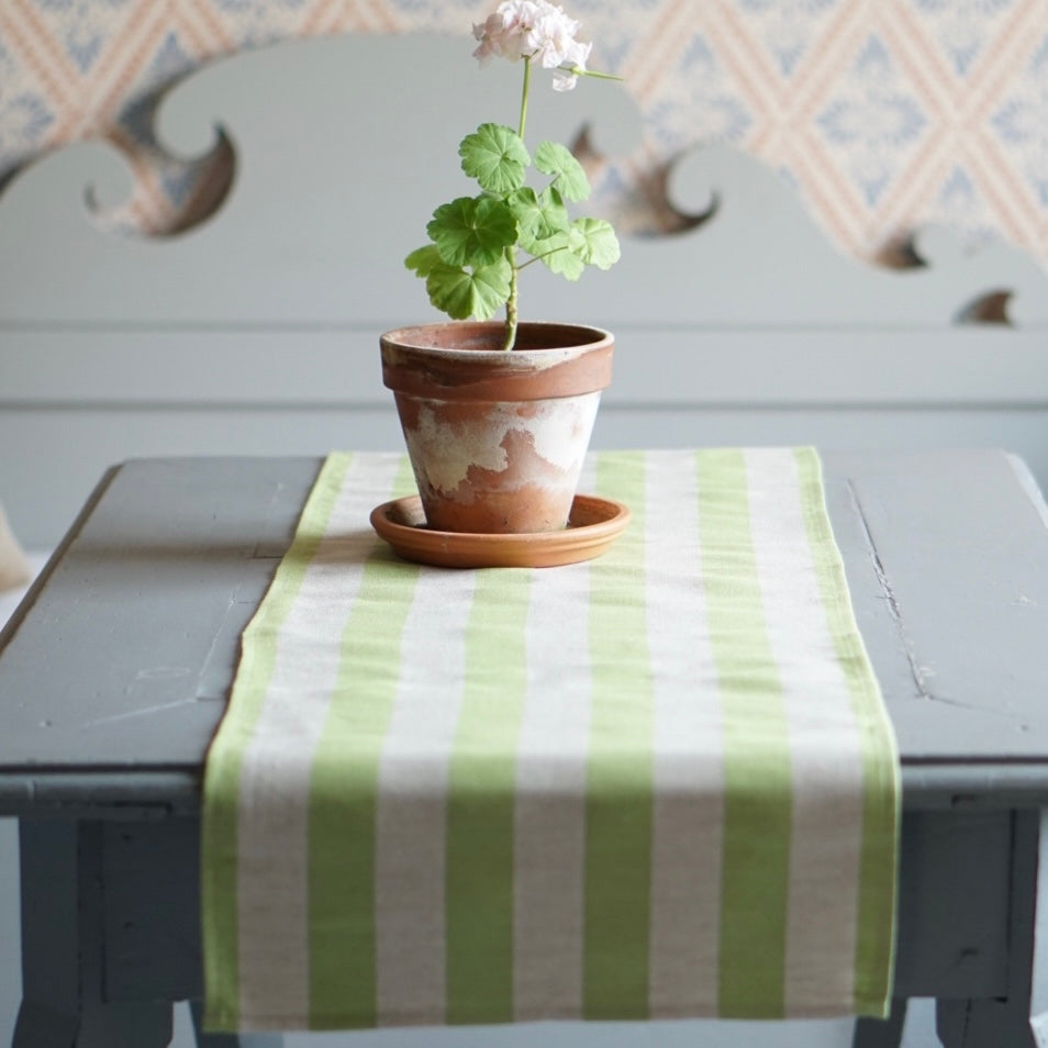 Tischläufer Streifen aus Halbleinen in hellgrün auf Tisch vpor Küchendsofa mit Pelargonie