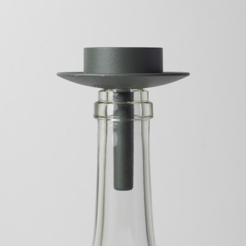 Teelichthalter aus Metall dunkelgrün auf weißer Glasflasche