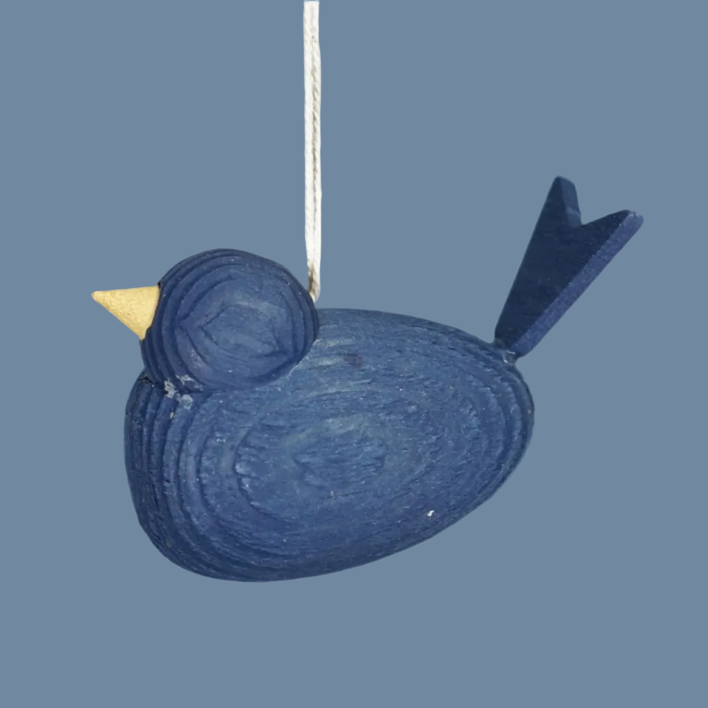 kleiner dunkelblauer Holzvogel an weißem Band vor mysblauem Hintergrund