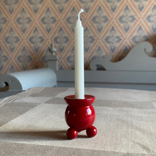 Traditioneller schwedischer Kugelkerzenhalter in rot auf einer Leinentischddecke vor einer Küchenbank