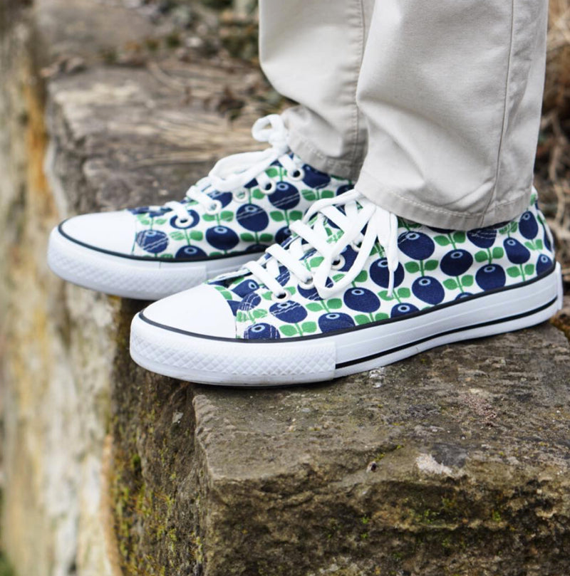 Sneakers/Turnschuhe Blaubeere angezogen und auf Mauer stehend
