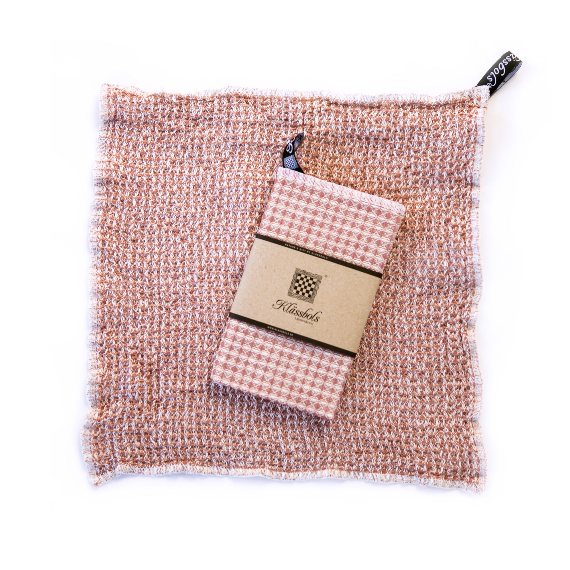 ein gewaschenes Spültuch Bubbel rosa Leinen Klässbols linneväveri Mys Shop mit einem neuen Spültuch mit Banderole obenauf liegend