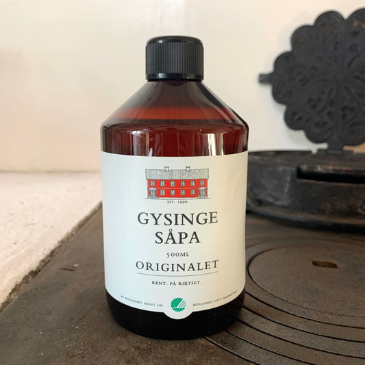Eine Flasche Leinölseife der Manufaktur "Gysinge Såpa" steht auf einem antiken Küchenofen.
